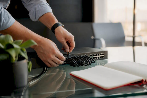 Hands connecting cables to a router device